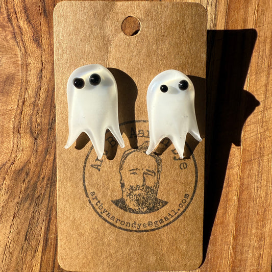 Frosted white glass ghost stud earrings with black eyes on a wood background