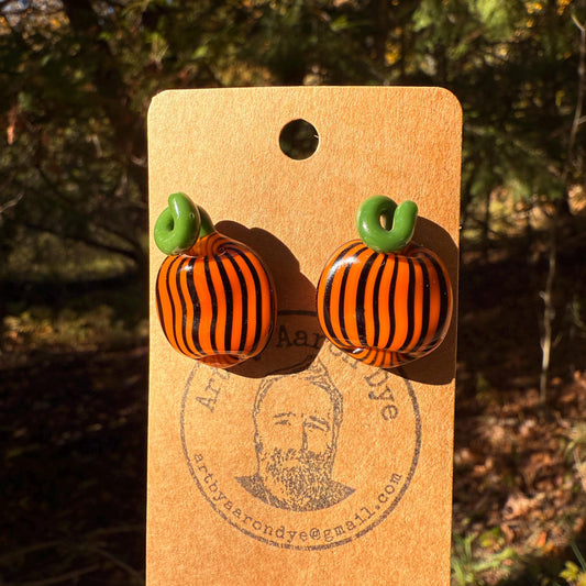 Orange blown glass pumpkin stud earrings with black stripes and a green top