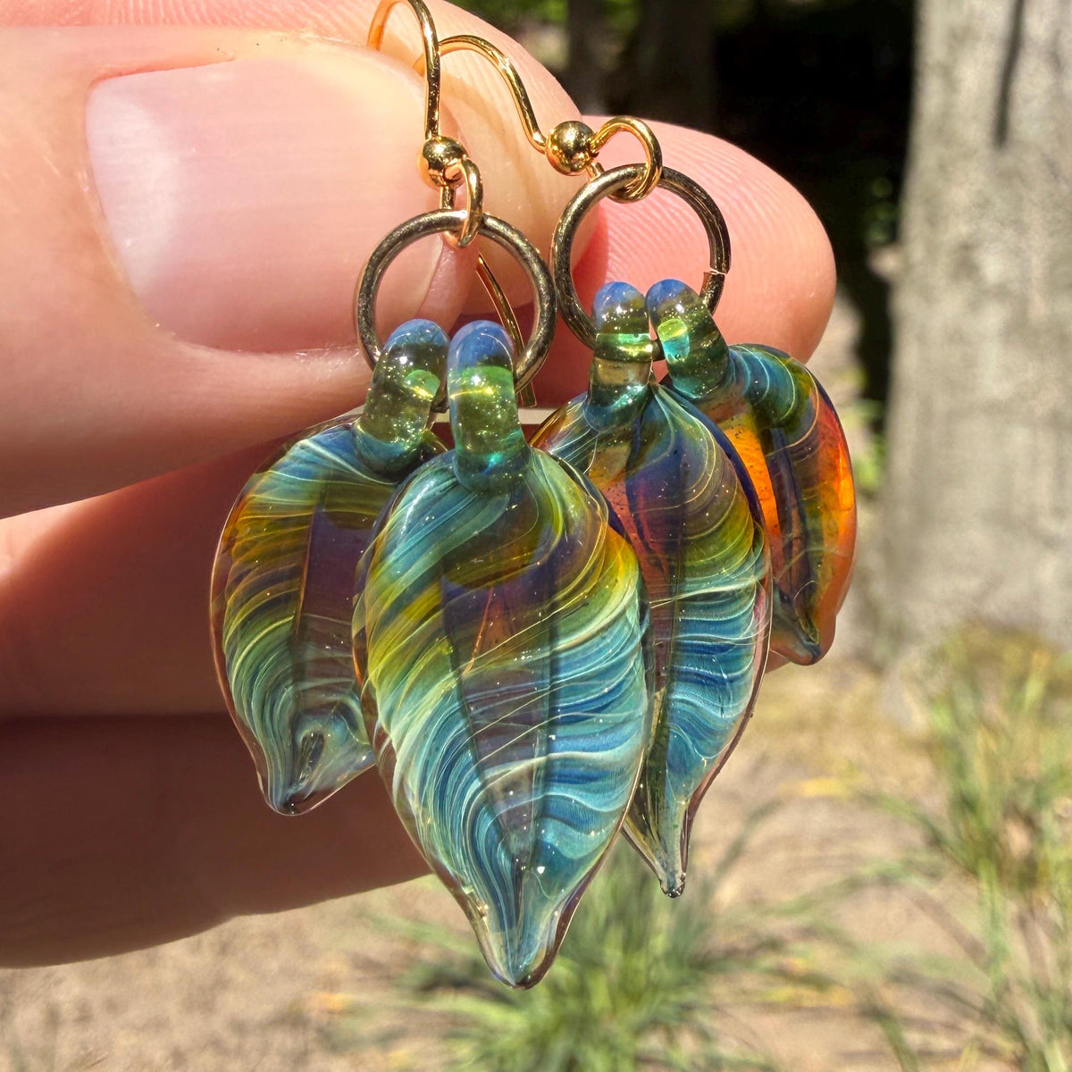 Iridescent hand blown glass feather earrings in teal, blue, green and gold on gold hooks